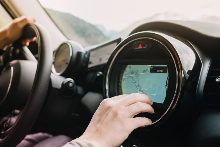 Man sitting in the car with black interior and looking at the new route laid by the navigator. Driver waiting for the itinerary to be made up before journey..