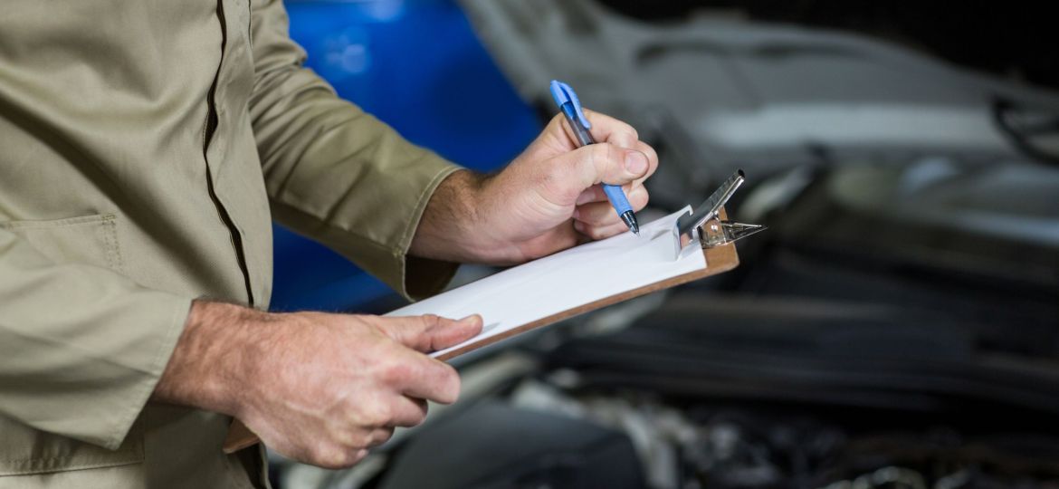 Mid-section of mechanic preparing a check list in repair garage
